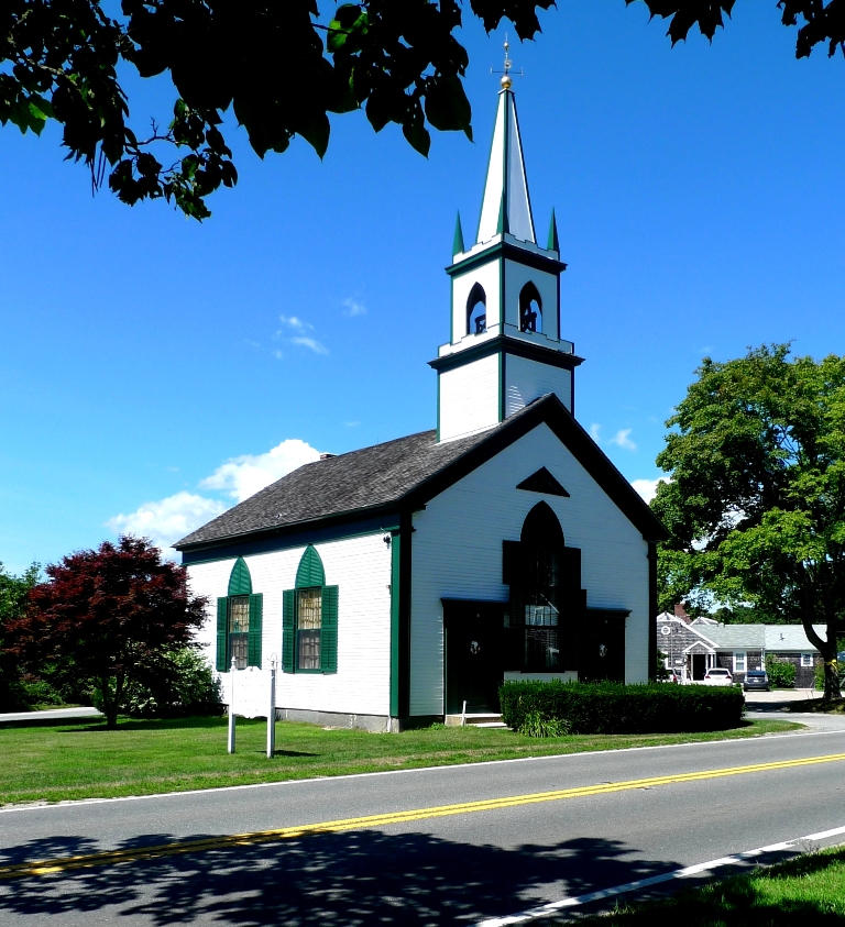 The historic white Waquoit Congregational Church with its green steeple, on a sunny Cape Cod day